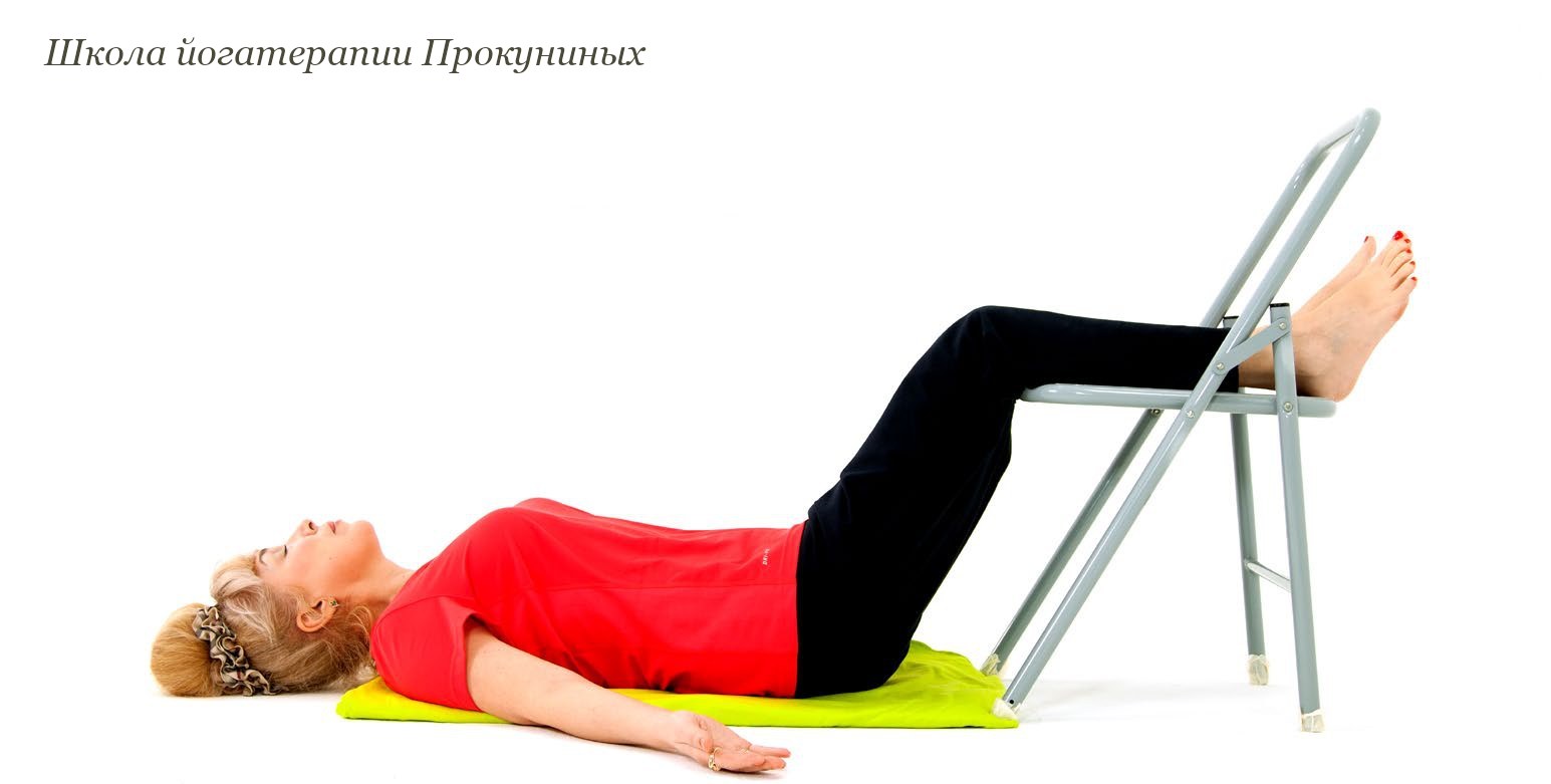 Елена Прокунина лежит на спине, голени лежат на сиденье стула